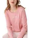 Woman wearing a pink long-sleeve top and white pants