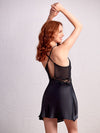 close-up image of a woman wearing a black satin baby-doll dress with V-neckline and embroidery detailing, looking seductive and confident