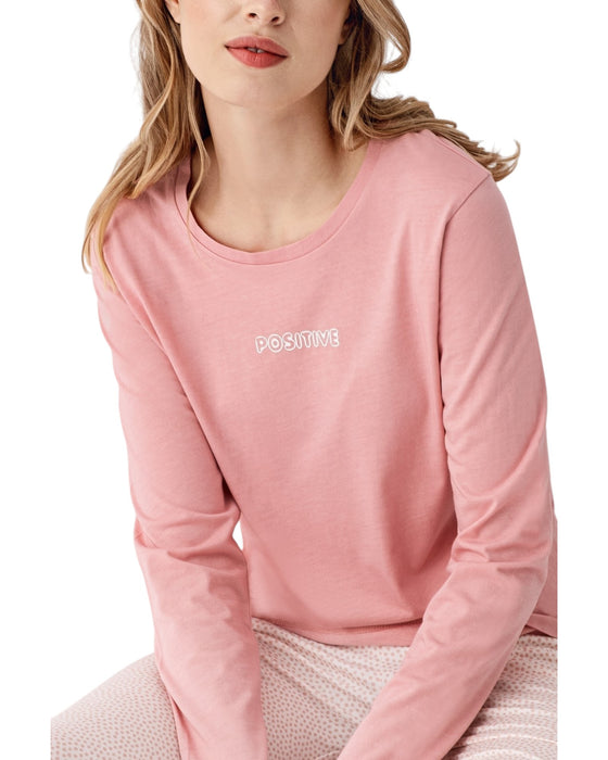 Woman wearing a pink long-sleeve top and white pants