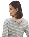Woman wearing a gray and white striped long-sleeve top with criss-cross back design