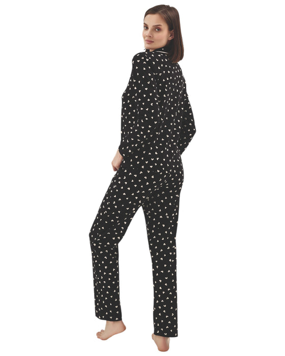 Woman wearing a black pajama set with pink heart pattern