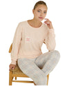 Woman wearing a light pink long-sleeve top and gray checkered pants 