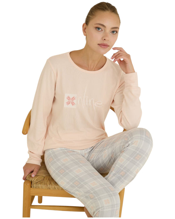Woman wearing a light pink long-sleeve top and gray checkered pants 