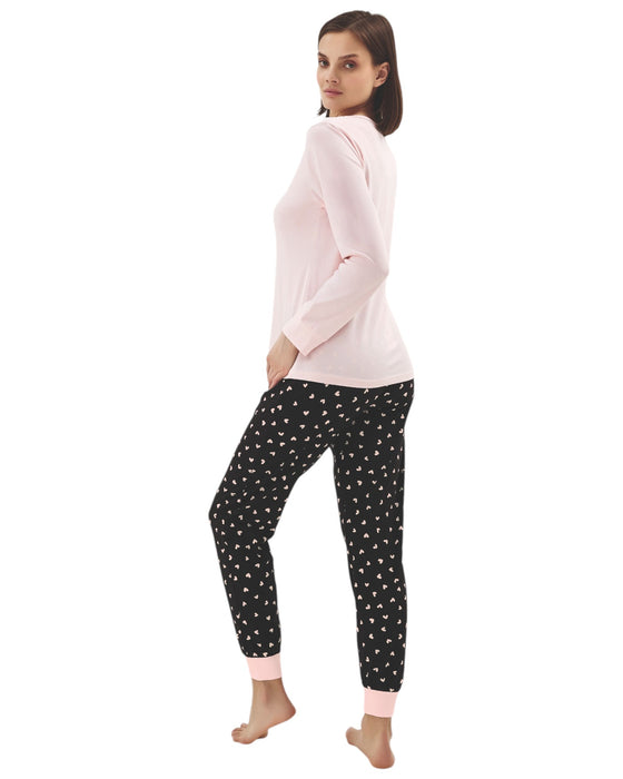 Woman wearing a pink long-sleeve top with cat print and black pants with hearts print 