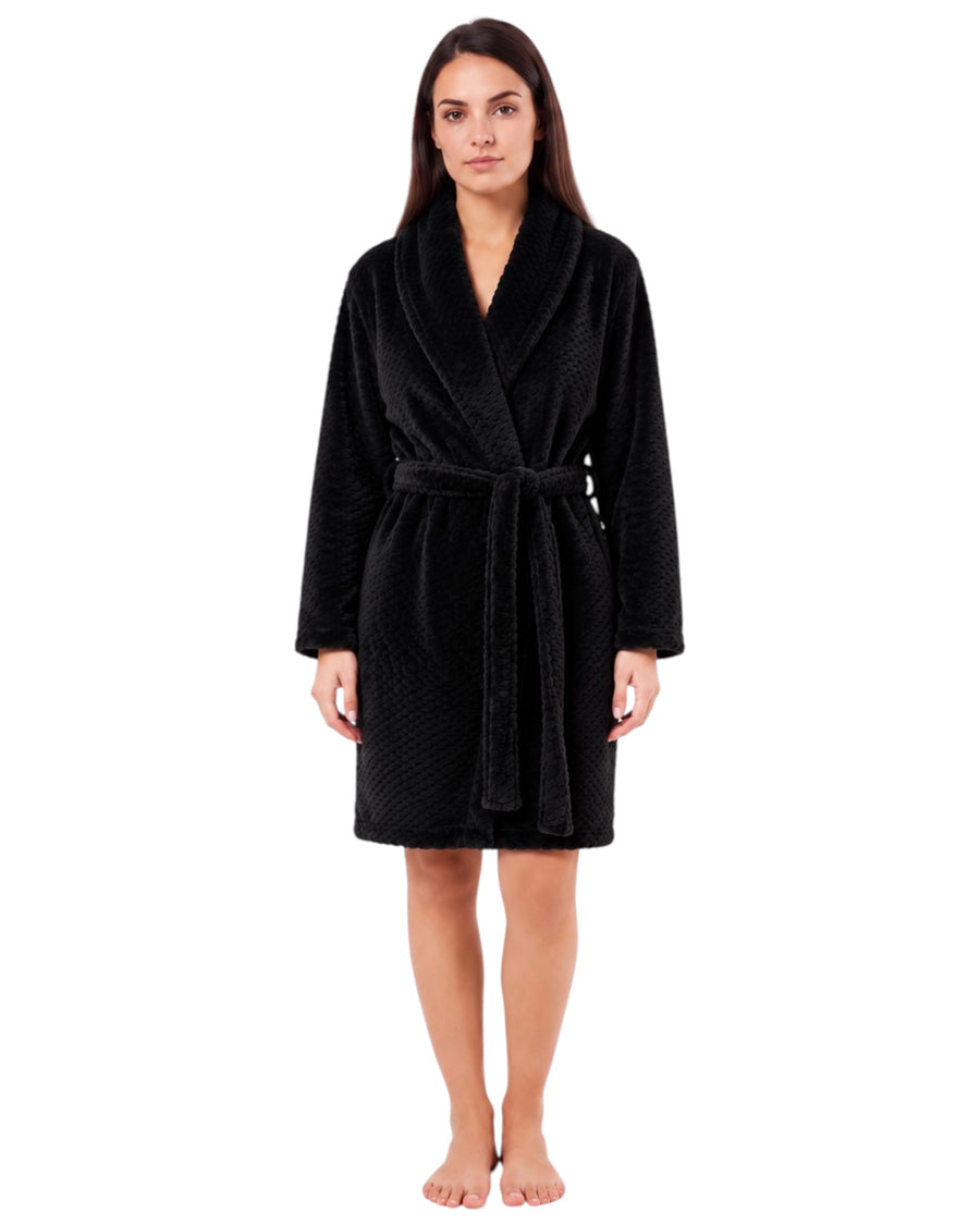 Woman wearing a black textured plush short robe with a shawl collar, long sleeves, and matching waist tie belt.