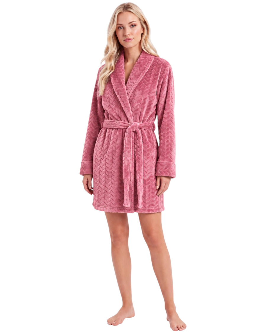 A woman modeling a pink textured plush bathrobe with a matching tie belt,