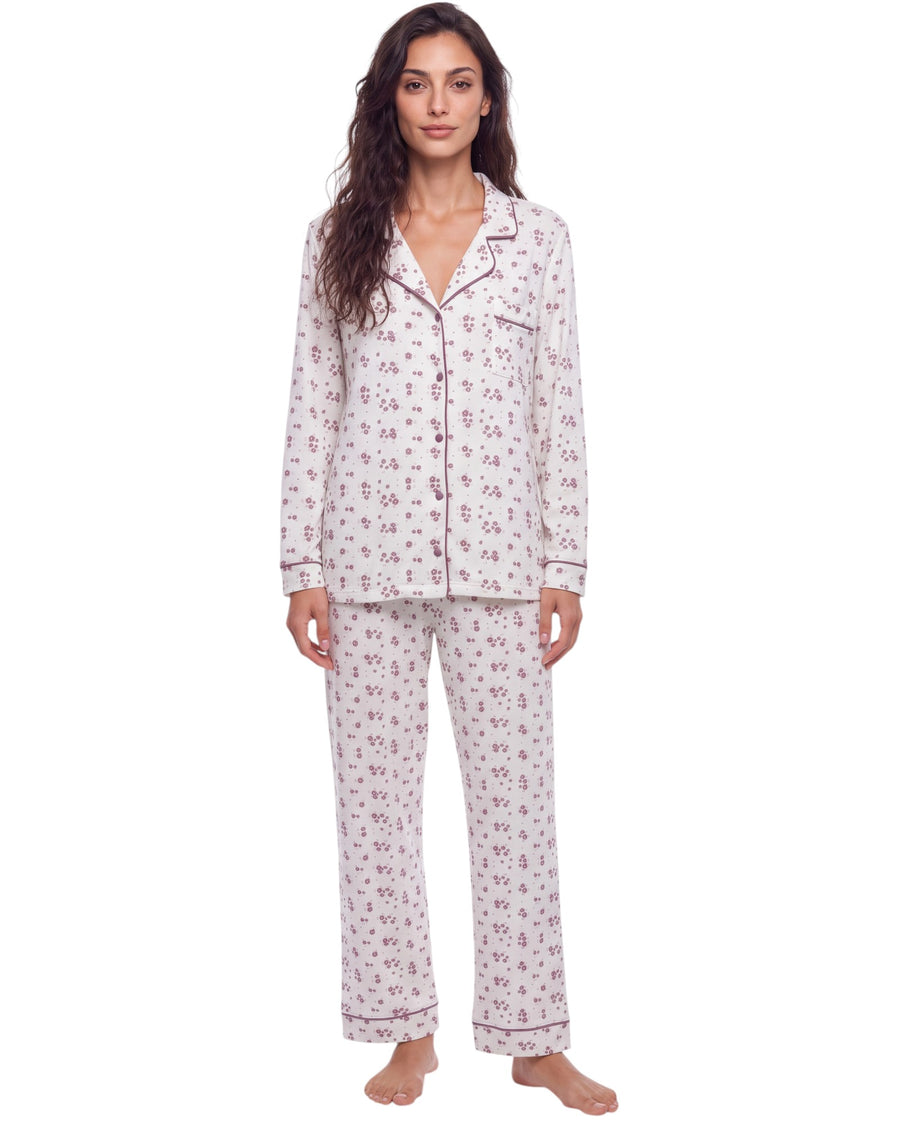 A woman modeling a two-piece pajama set with a white base and a small pink floral pattern, featuring a button-up long-sleeve top and matching pants
