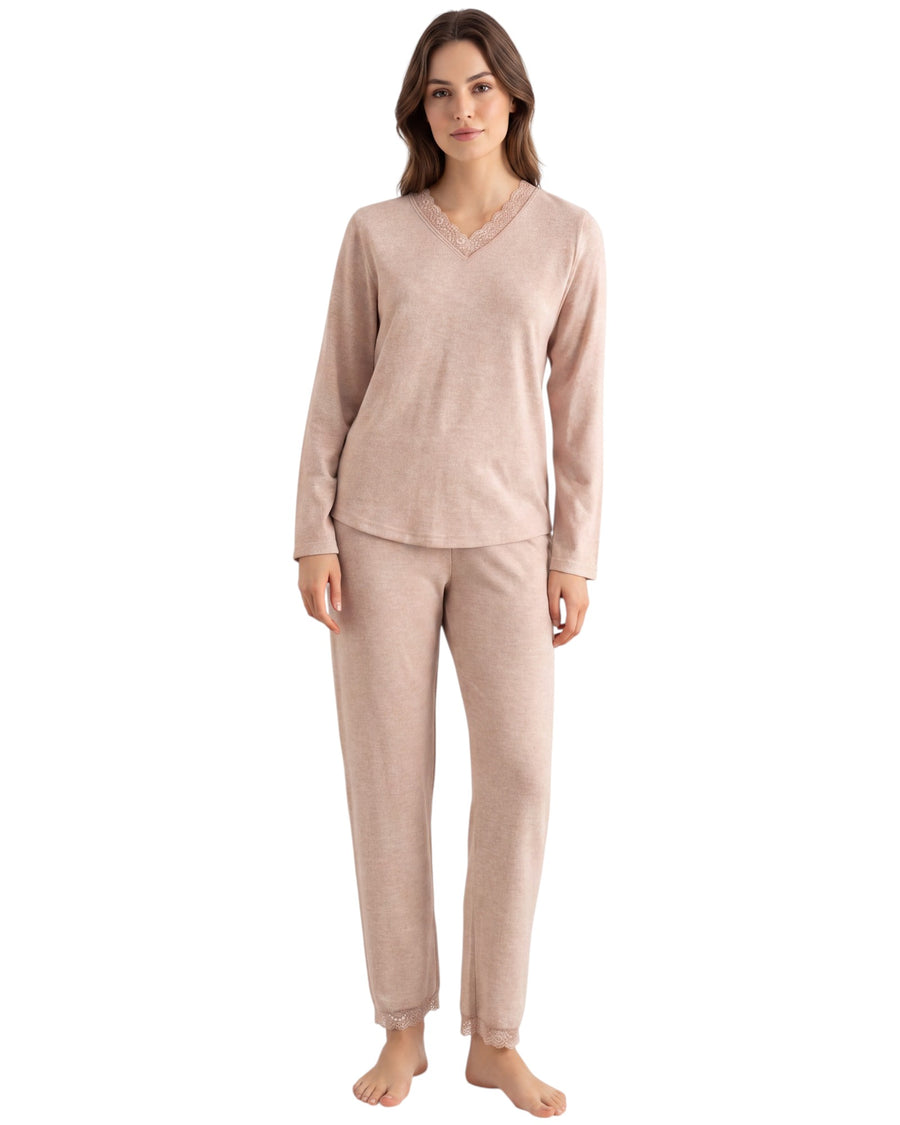 A woman modeling a two-piece pajama set in a light blush pink color, featuring a long-sleeve V-neck top and matching pants
