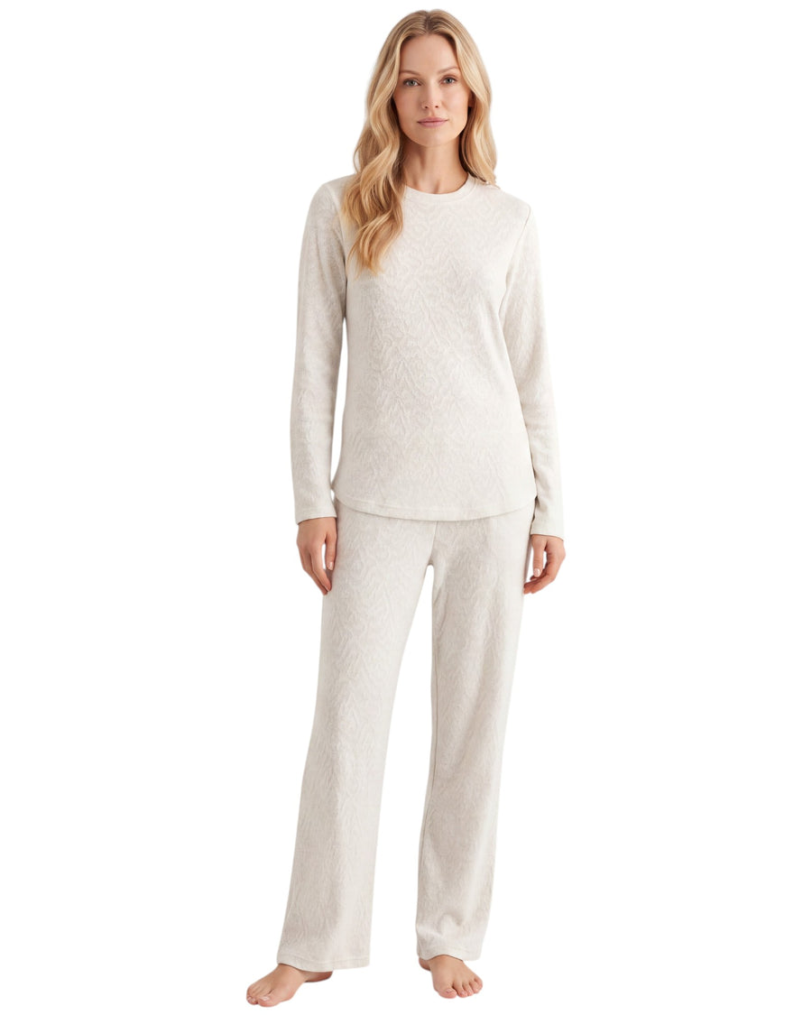 A woman modeling a two-piece cream-colored textured pajama set consisting of a long-sleeve top and matching pants