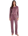 A woman modeling a two-piece velour pajama set in dusty mauve with a small gold embroidered logo on the chest