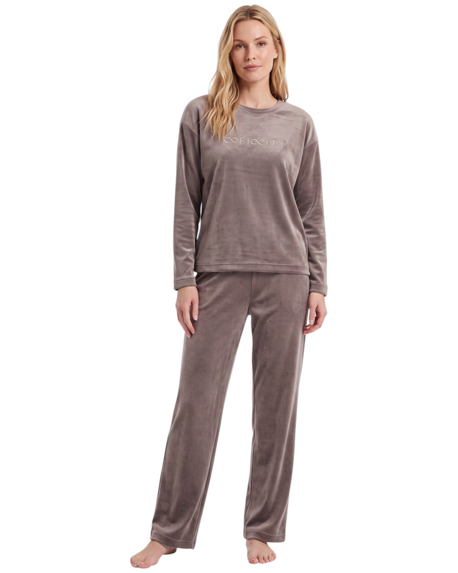 A woman modeling a two-piece long-sleeve pajama set in a dusty taupe color, featuring a matching top with subtle text and coordinating pants