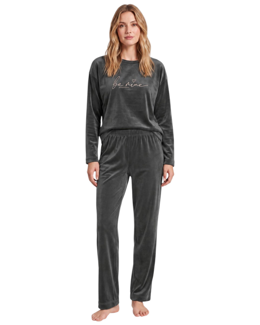 A woman modeling a dark gray two-piece velour pajama set with a long-sleeve top featuring 'be mine' script embroidery and matching pants