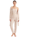 A woman modeling a light beige knit loungewear set consisting of a camisole, matching jogger pants, and a long open-front cardigan