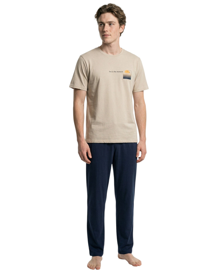 Man wearing a beige t-shirt and navy pants pajama set