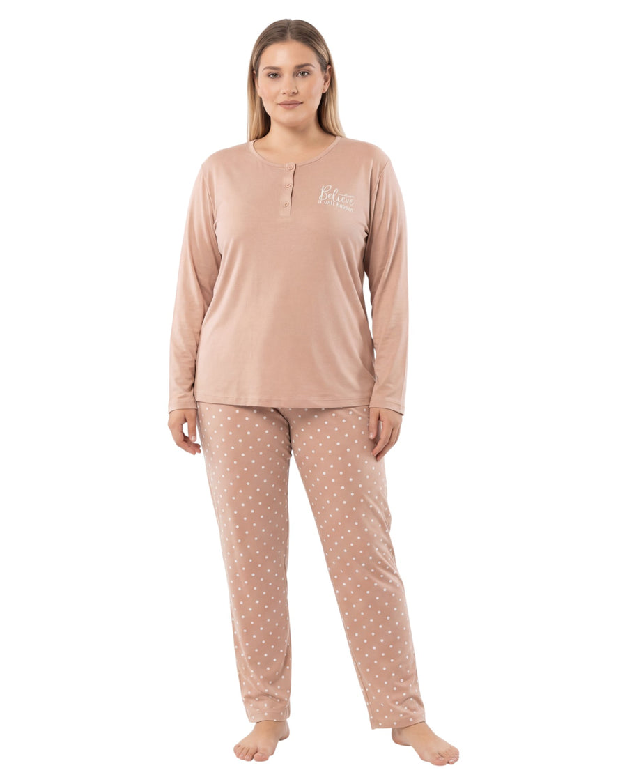 Woman wearing a beige long-sleeve top and polka dot pants on a white background