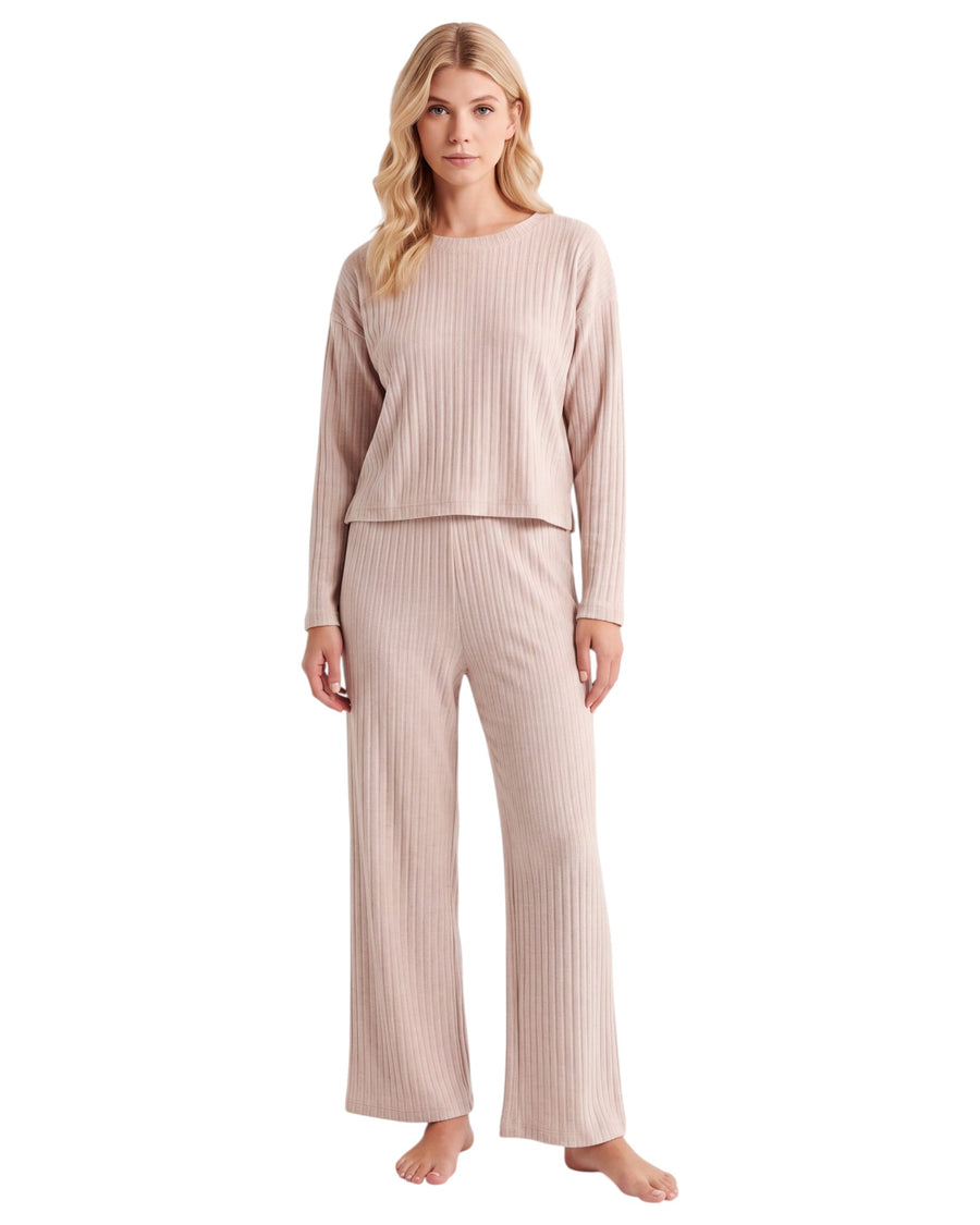 A woman modeling a two-piece ribbed knit loungewear set in a light blush pink color, consisting of a long-sleeve cropped top and matching wide-leg pants