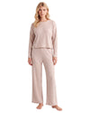 A woman modeling a two-piece ribbed knit loungewear set in a light blush pink color, consisting of a long-sleeve cropped top and matching wide-leg pants
