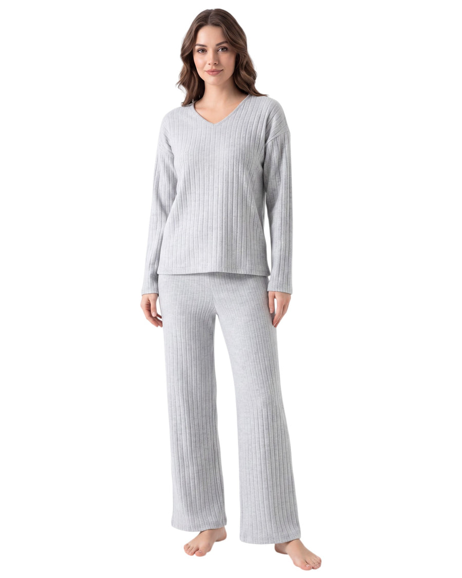 A woman modeling a light gray ribbed two-piece pajama set with a long-sleeve V-neck top and matching wide-leg pants