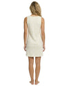 Woman wearing a cream sleeveless dress with a subtle pattern