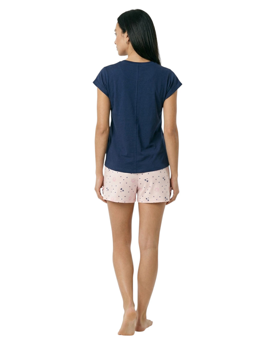 Woman wearing a navy blue top and light pink shorts with a subtle pattern 