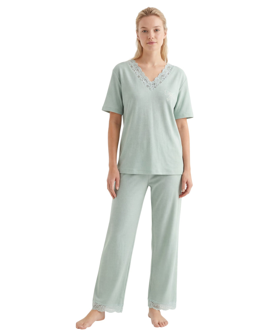 Woman wearing a light green pajama set with lace trim details