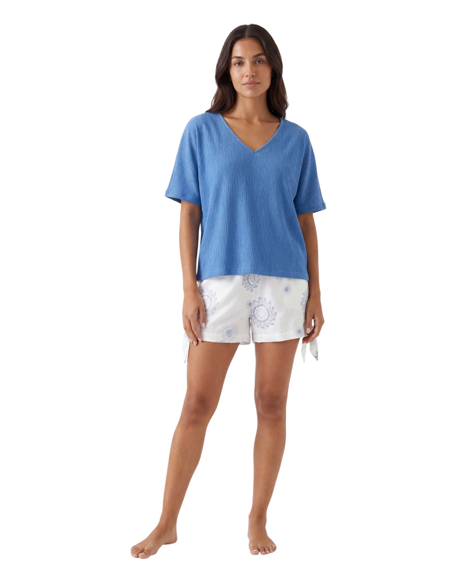 Woman wearing a blue top and white shorts with a sun pattern 