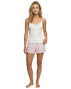 Woman wearing a white tank top with lace details and pink shorts 