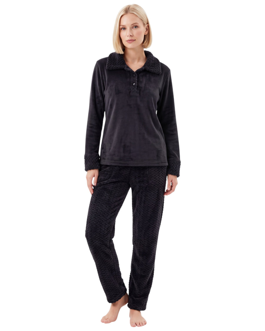 Woman wearing a plush pajama set featuring a long-sleeve top with a textured collar, buttoned neckline, matching cuffs, and textured long pants.