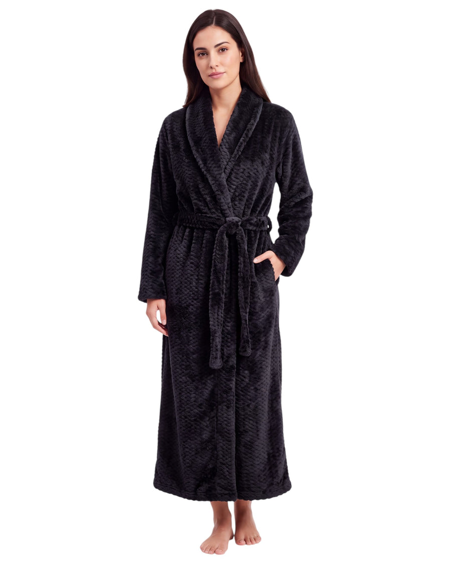Woman wearing a black textured plush long robe featuring long sleeves, a shawl collar, side pockets, and an adjustable waist belt.