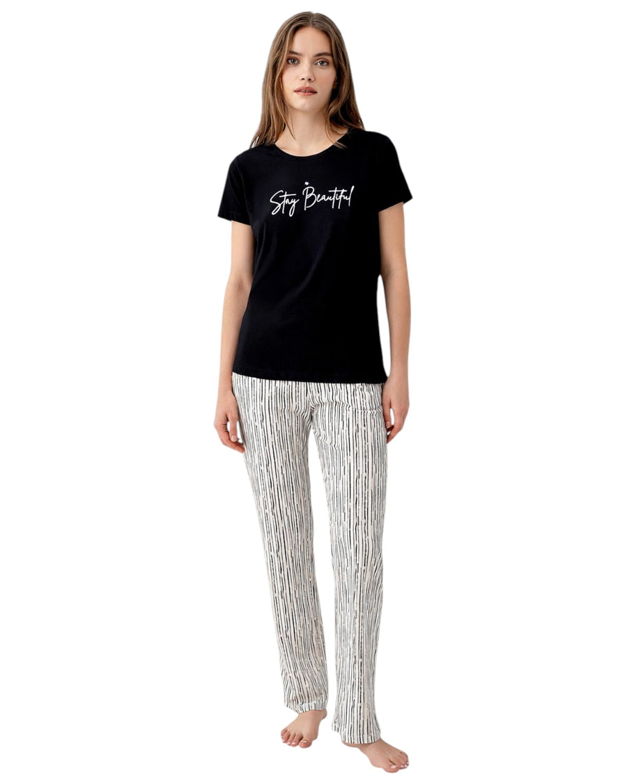 Woman wearing a black t-shirt with 'Stay Beautiful' text and patterned pants