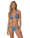 Model wearing a blue wave print triangle bikini set with halter tie top and side-tie bottoms in a shimmering textured fabric