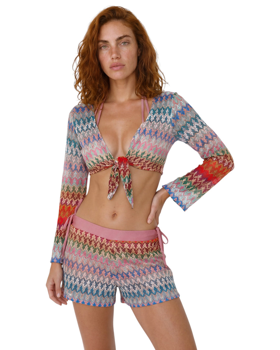 Model wearing multicolor knit beach cover-up shorts with a relaxed fit and vibrant zigzag pattern in pink, blue, red, and neutral tones.