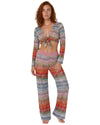 Model wearing a multicolor knit tie-front cover-up top with long sleeves and vibrant zigzag pattern in pink, blue, red, and neutral tones.
