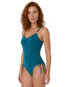 Model wearing a teal one-piece swimsuit with adjustable side ties and gold starfish strap details.