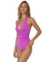 Woman wearing a magenta halter one-piece swimsuit with plunge neckline, ruched waist detail, open back, and adjustable neck tie