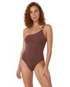 Model wearing a chocolate brown one-shoulder swimsuit with gold-tone ring detail, asymmetric neckline, and open back design.