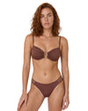 Model wearing a chocolate brown bikini set with gold-tone U-bar detail, adjustable straps, and strappy side bikini bottoms.