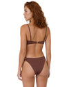 Model wearing a chocolate brown bikini set with gold-tone U-bar detail, adjustable straps, and strappy side bikini bottoms.