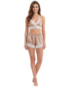 A woman modeling a two-piece satin pajama set with a camisole top and matching shorts, featuring a champagne beige color with white lace trim
