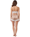 A woman shown from the back wearing a two-piece satin pajama set in a light champagne pink with white floral lace trim, consisting of a spaghetti-strap crop top and matching shorts.