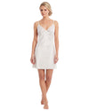 A woman modeling a short white slip dress with thin straps, lace trim at the neckline, and a scalloped hem 