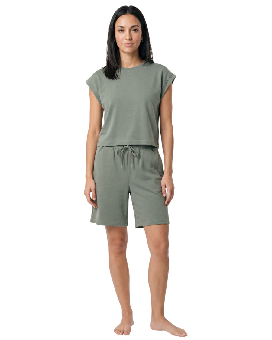 Model wearing a sage green lounge set with a relaxed cap sleeve top and matching drawstring shorts.