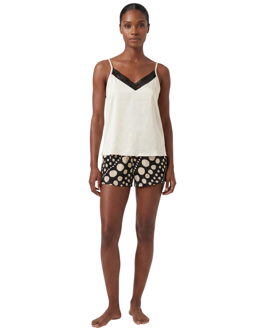 Woman wearing a white tank top with black trim and polka dot shorts 