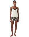 Woman wearing a white tank top with black trim and polka dot shorts 