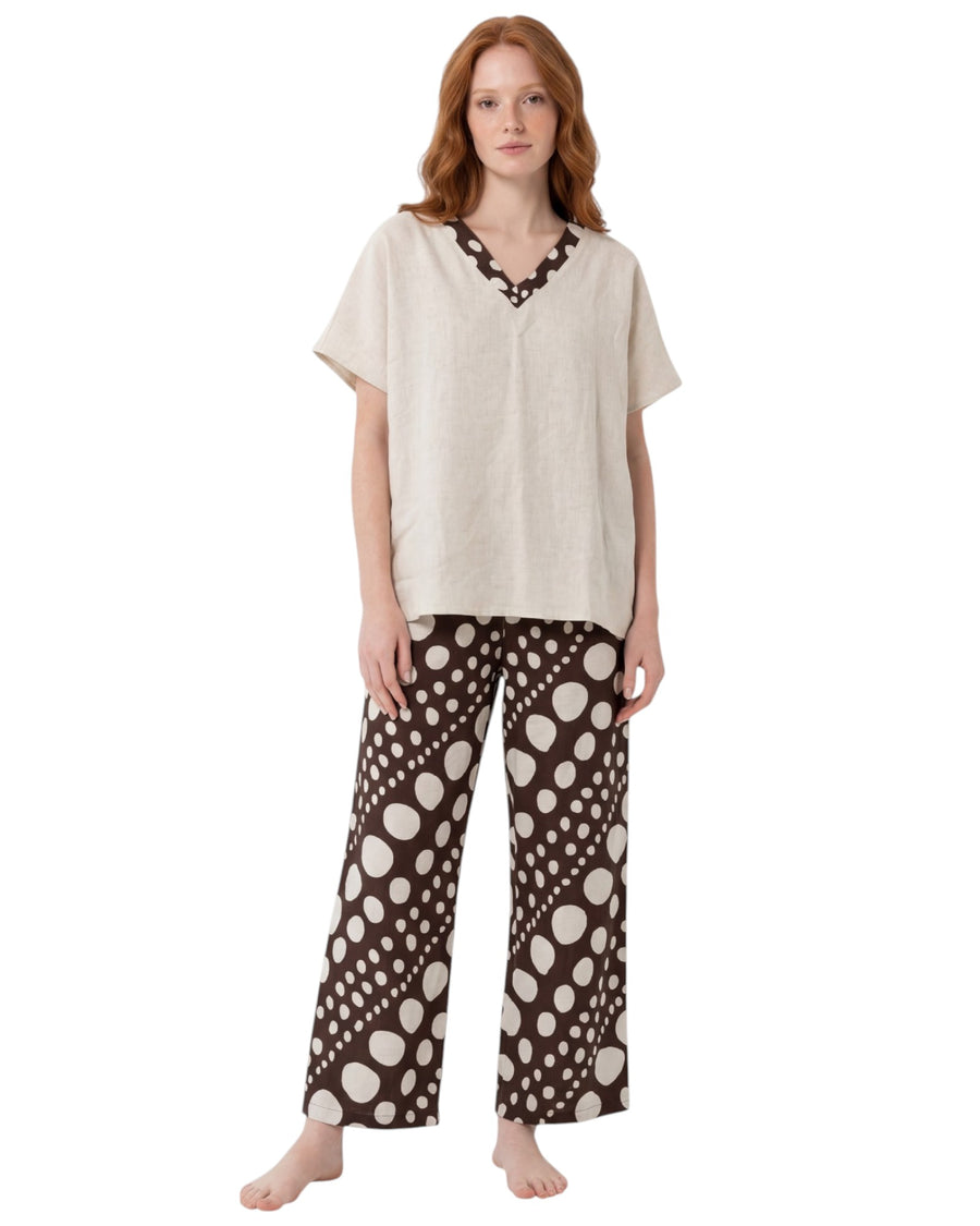 Model wearing a relaxed beige lounge top with wide-leg brown polka dot printed pants.