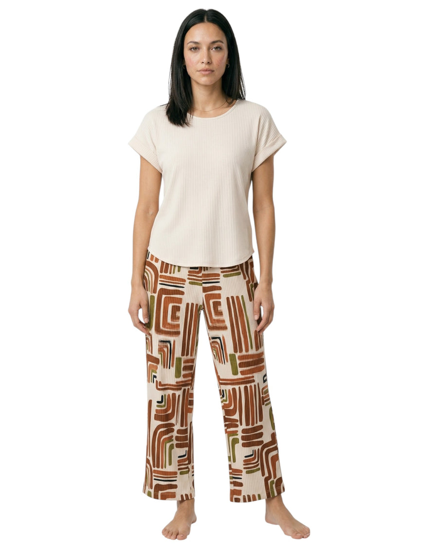 Model wearing a neutral ribbed lounge top with geometric print wide-leg pants in earthy tones.