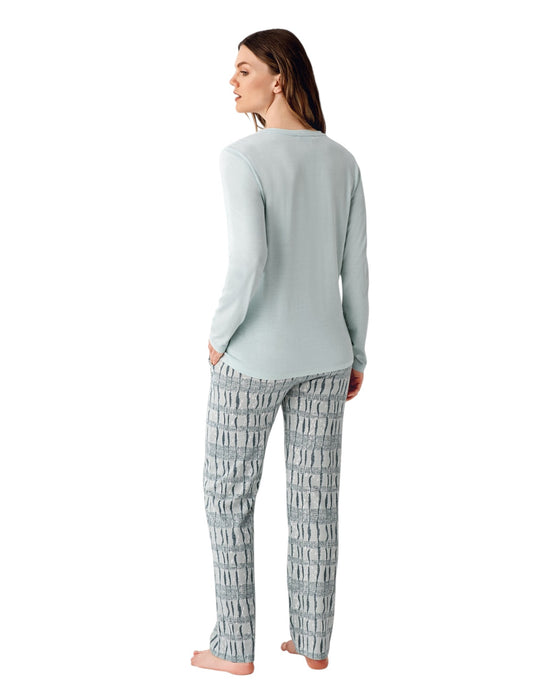 Woman wearing a light green long-sleeve top and patterned pants 