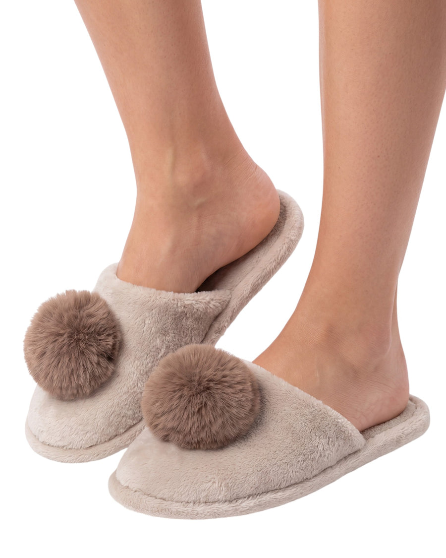 A pair of plush taupe slip-on slippers with large brown faux-fur pom-poms on the top